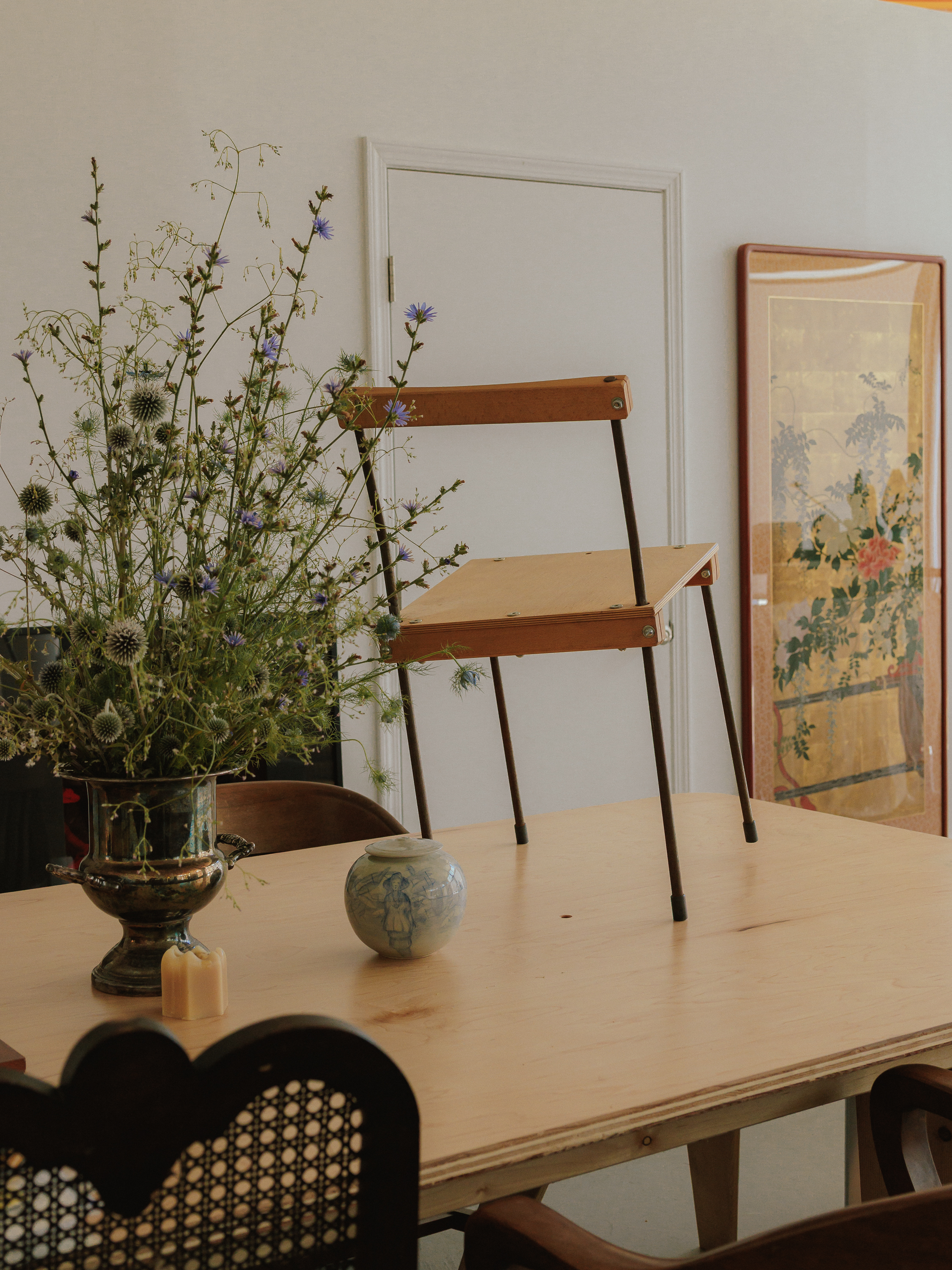 An interior arrangement with flowers, a chair, and framed artwork