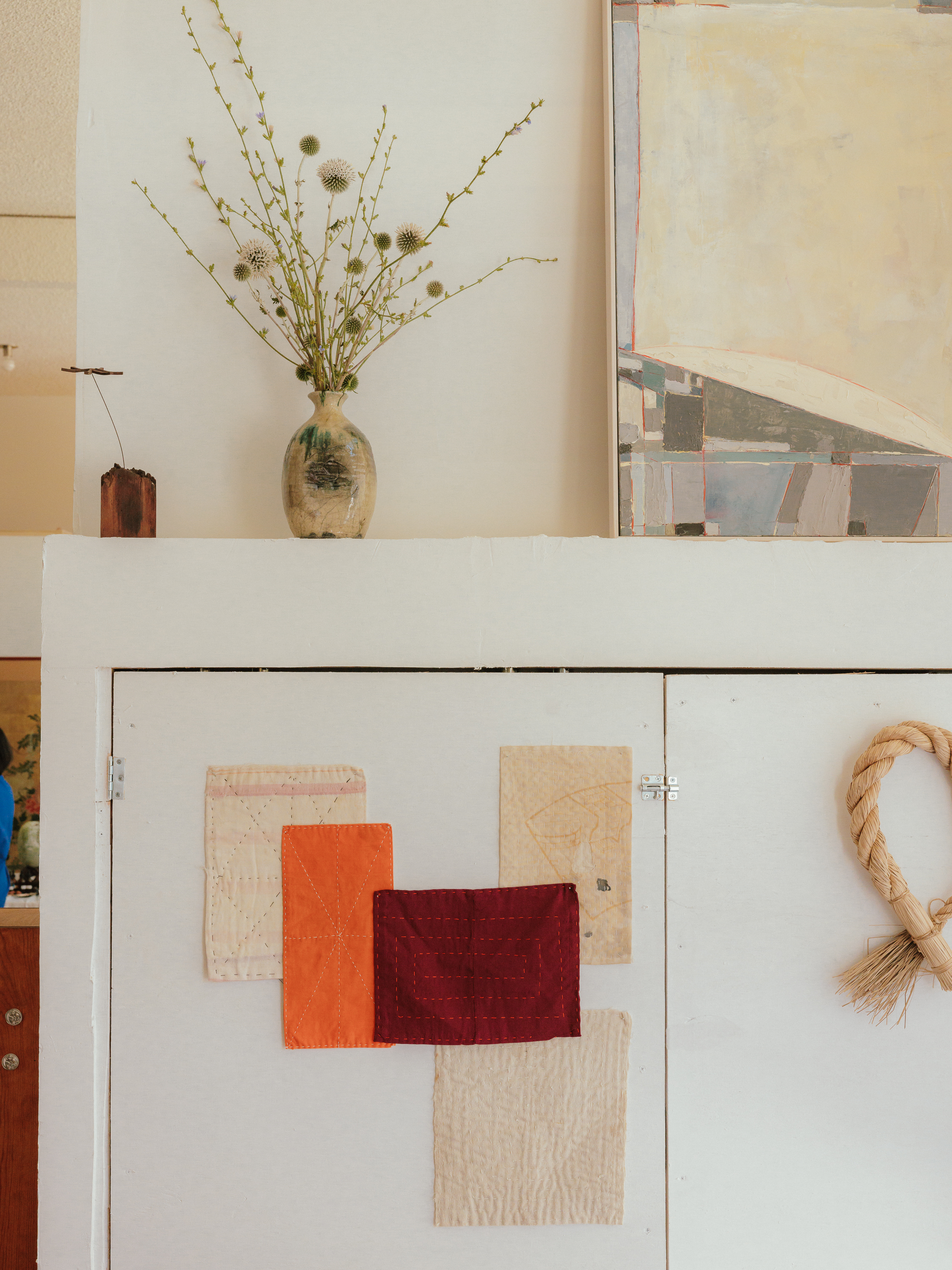 An interior vignette with artwork, flowers, and stitched textiles