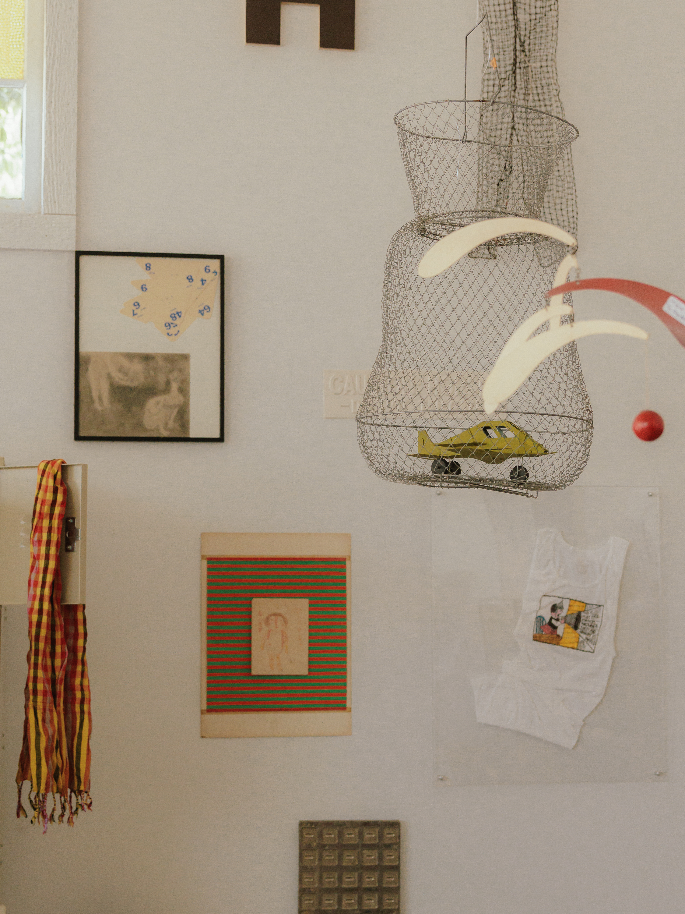 An interior wall arranged with artwork and sculptural objects