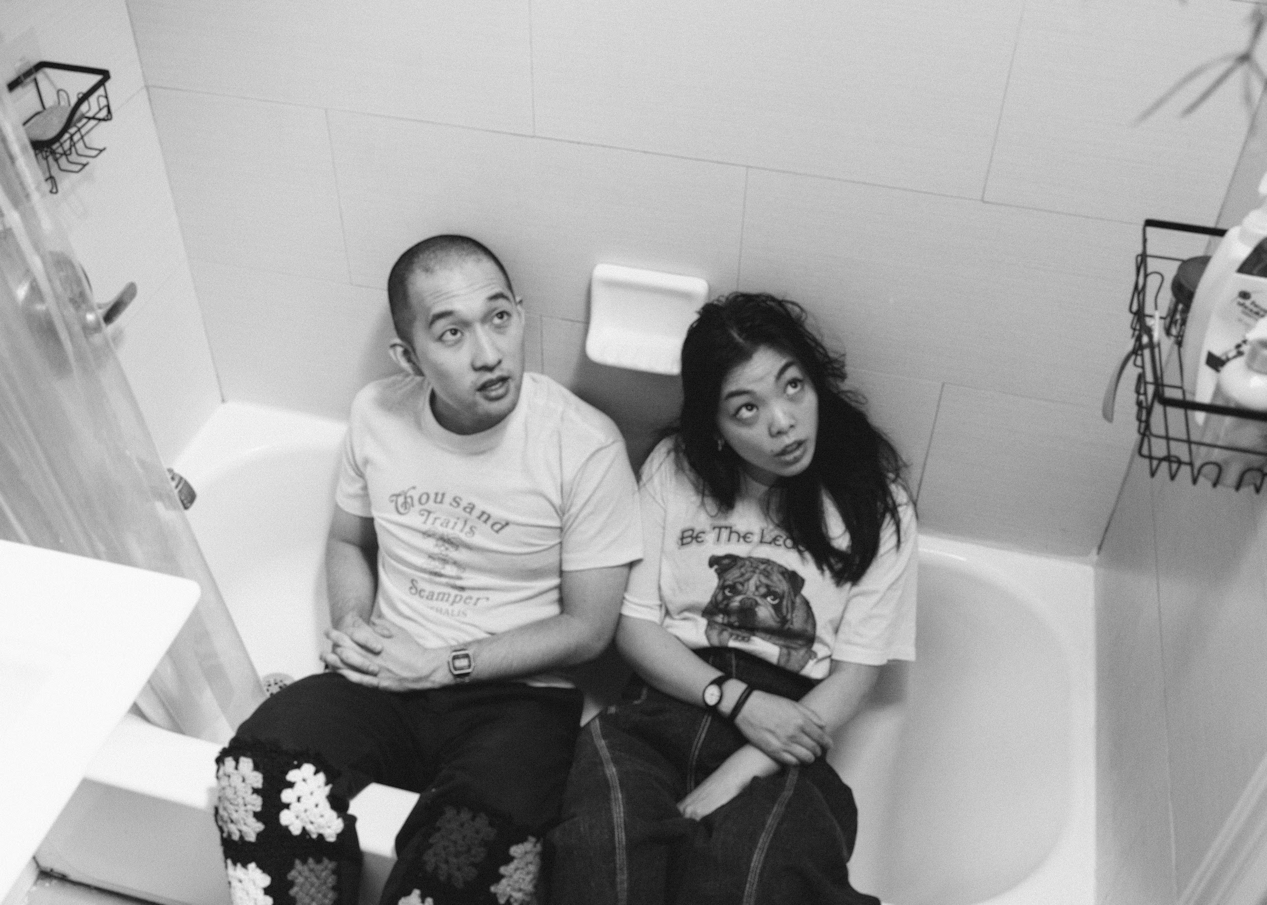 A black-and-white portrait of two people sitting in a bathtub