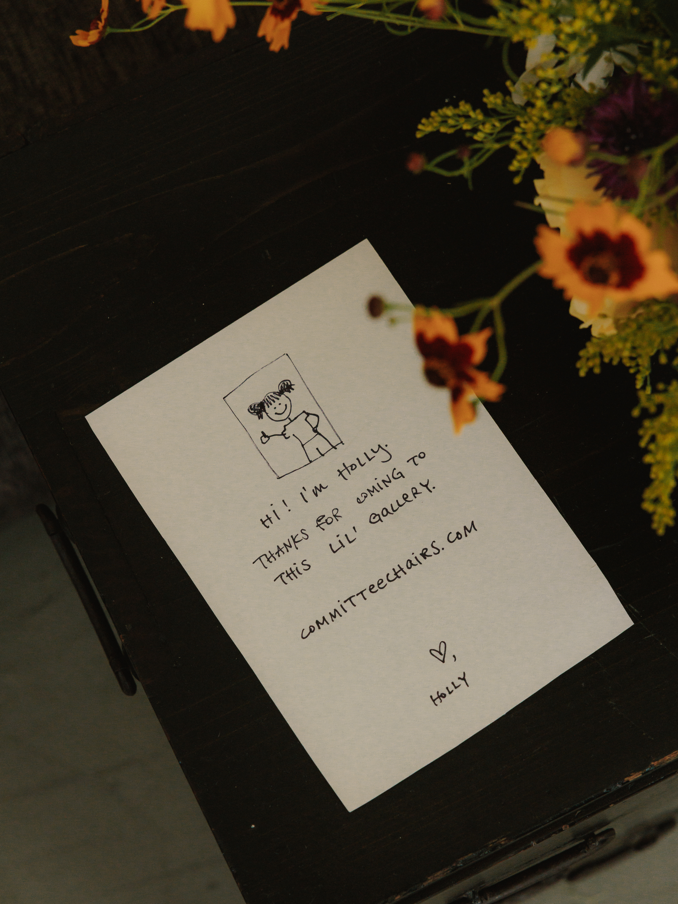 A handwritten thank-you note beside a flower arrangement