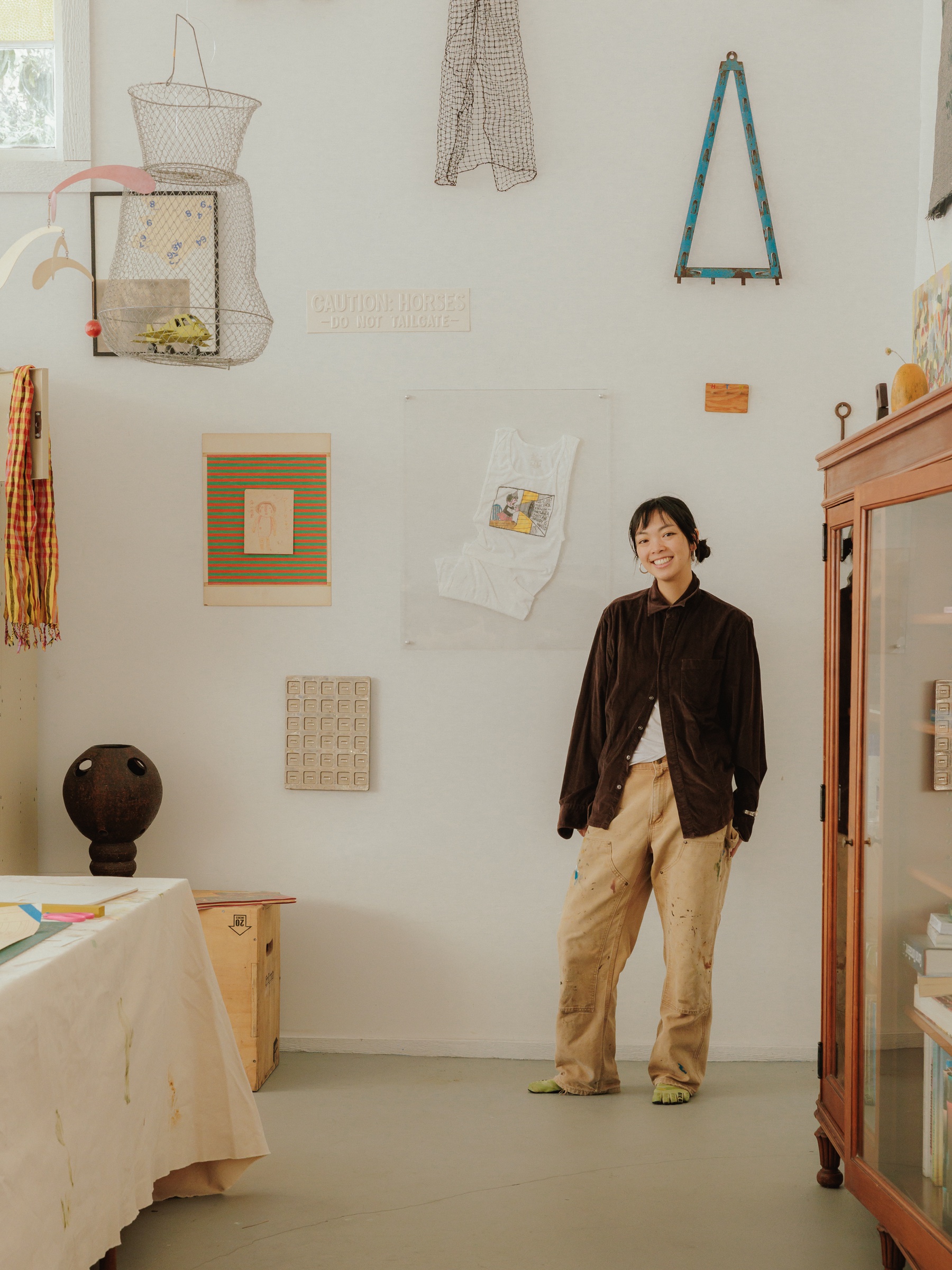 Portrait of Holly in a studio filled with collected artwork
