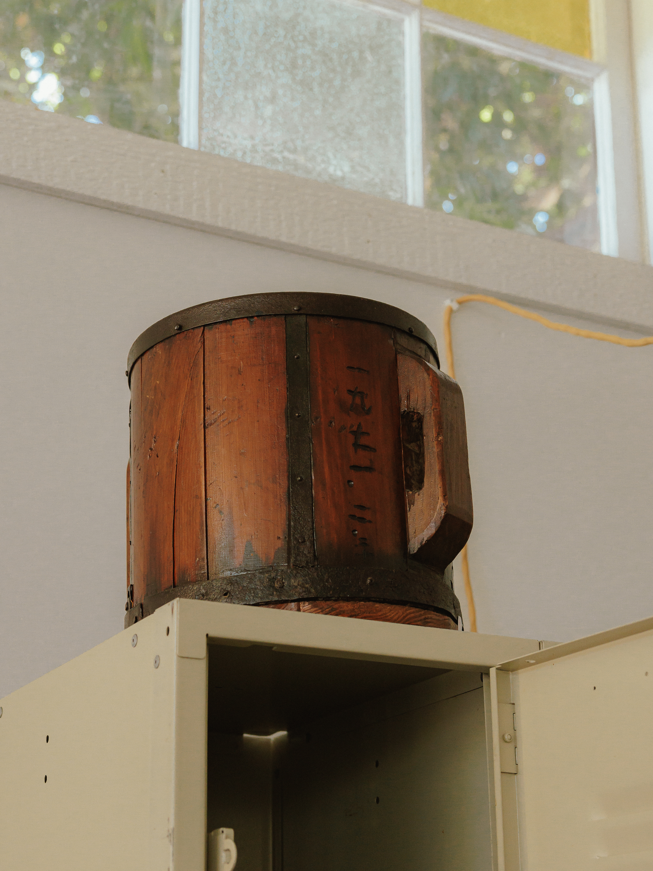 A wooden vessel displayed above a metal cabinet beneath a studio window
