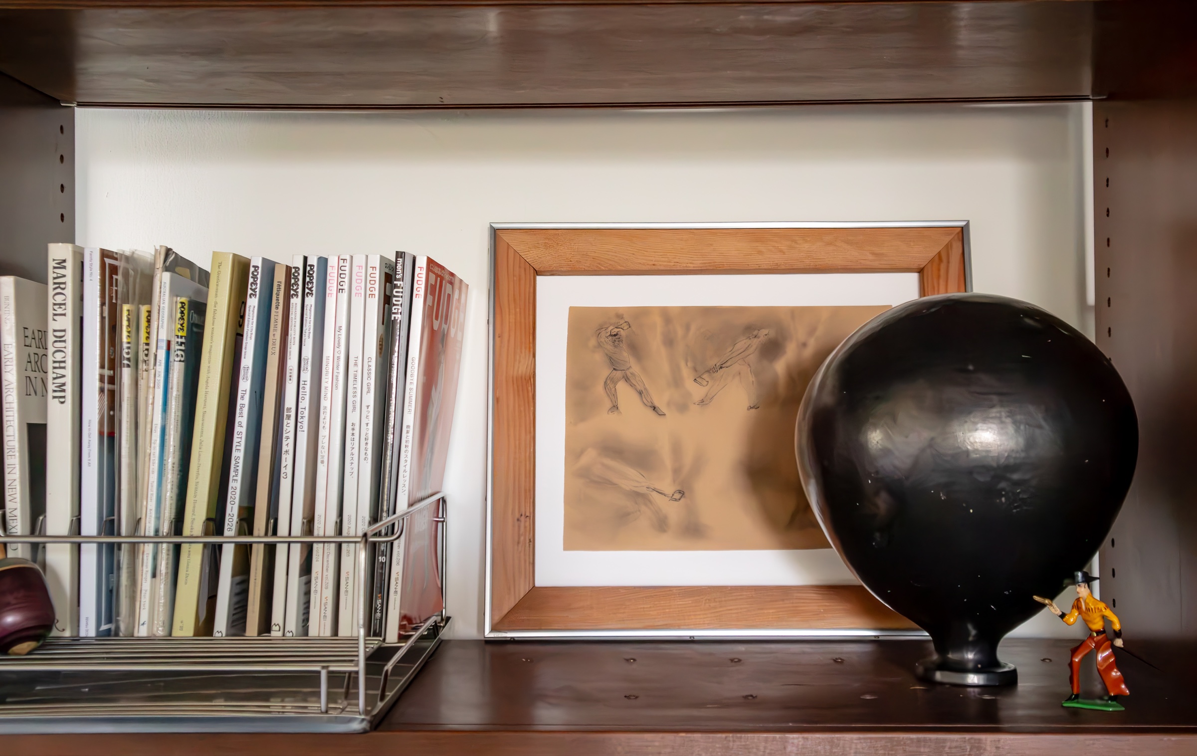 Books, framed artwork, a black vessel, and a small figurine