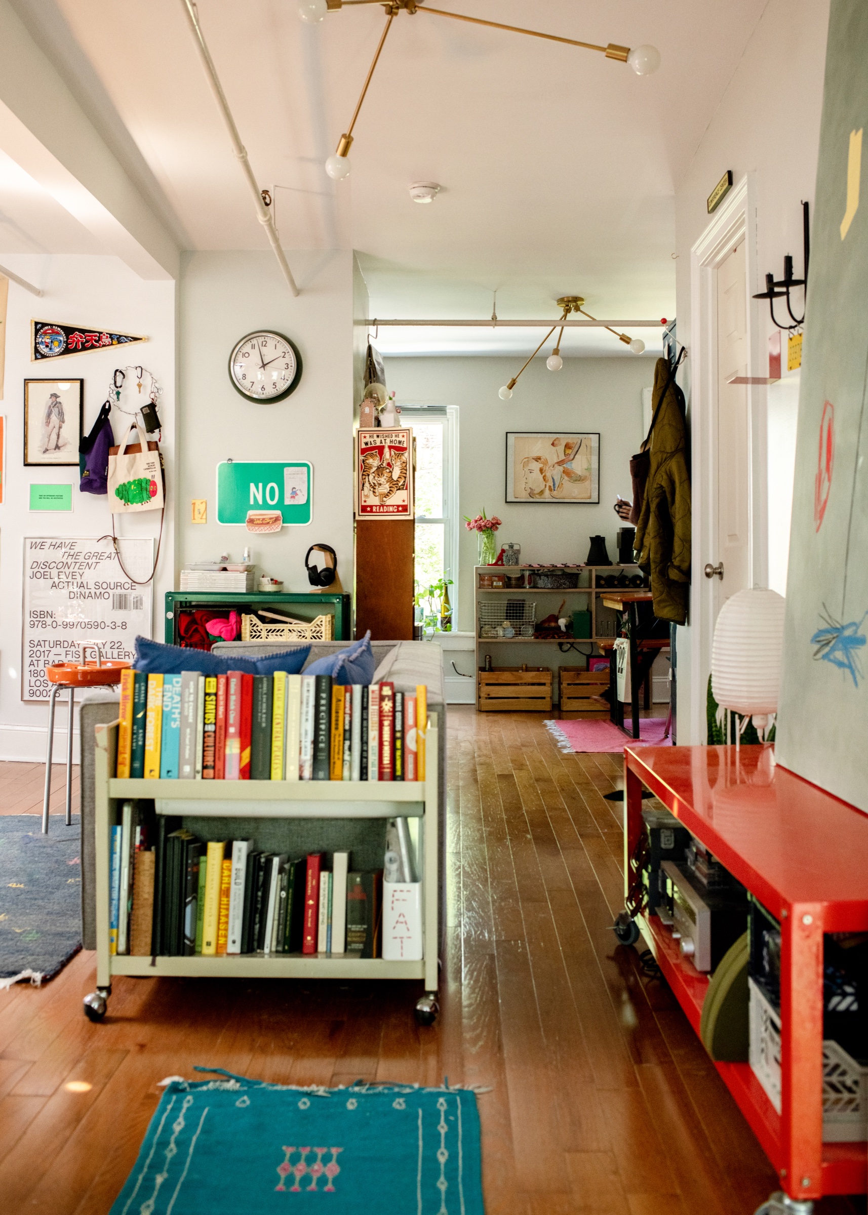 A living room with books, art, plants, and red furniture