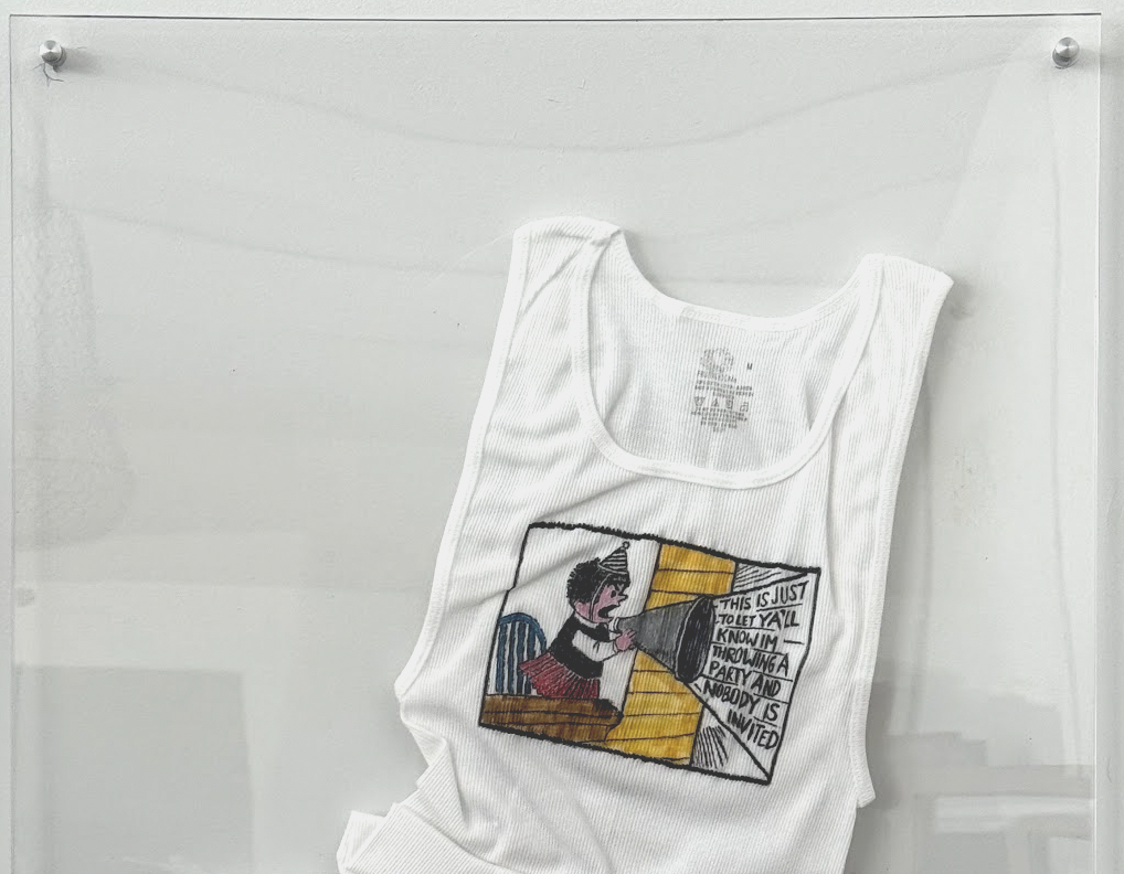 An illustrated tank top displayed behind glass